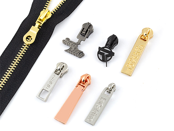 Luxury metal zipper pullers in various designs and colors with a black zipper