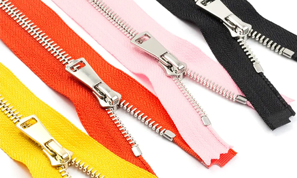 Multicolored metal zippers in black, pink, red, and yellow with silver teeth and pulls.