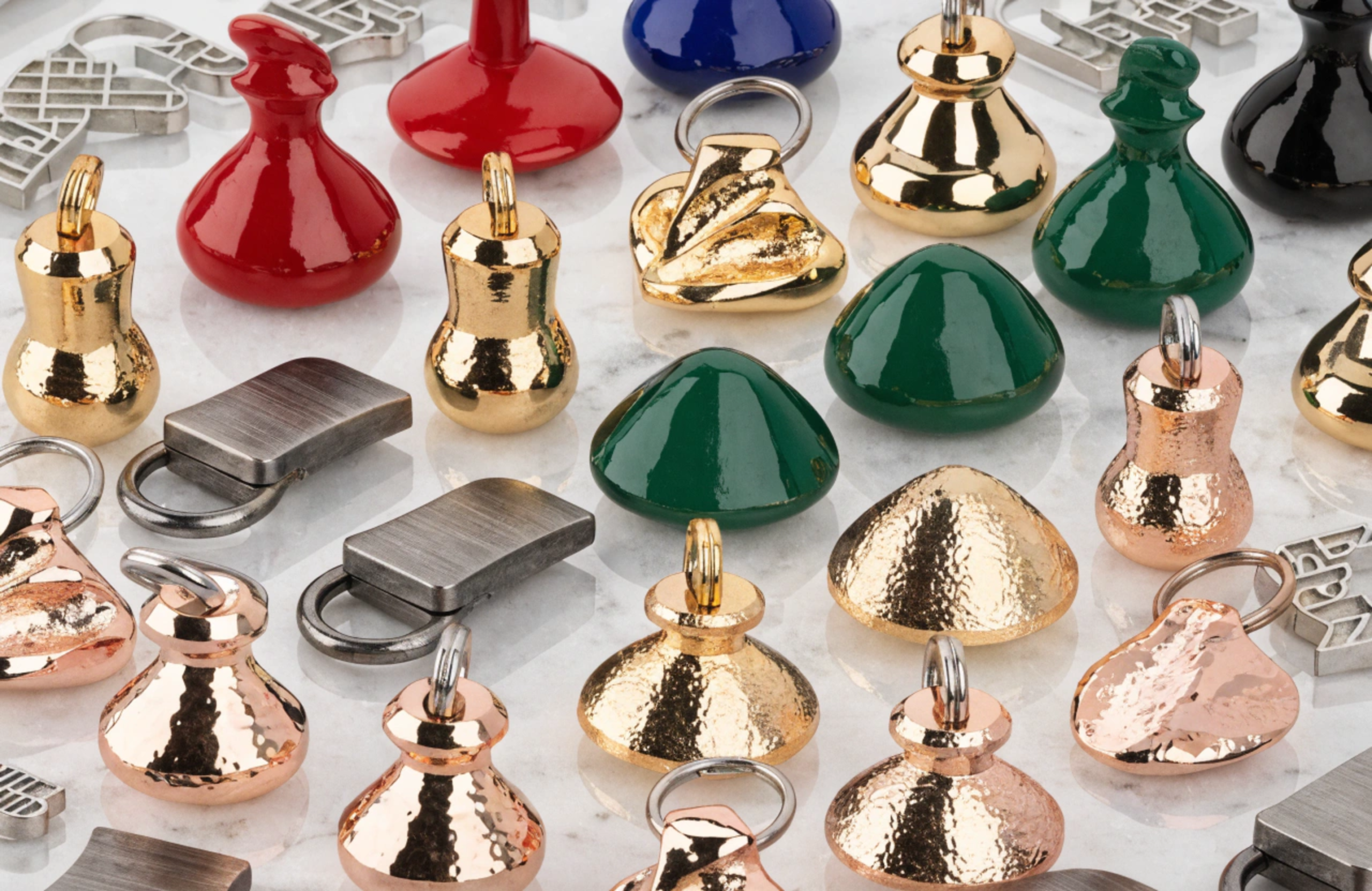 An assortment of zipper pullers showing different shapes and colorful enamel finishes