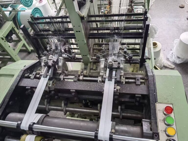 Close-up view of precision separating zippers being manufactured on an automated production machine.